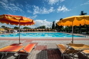 卡斯特努沃德加尔达坎普瑞娜酒店的一个带椅子和遮阳伞的大型游泳池