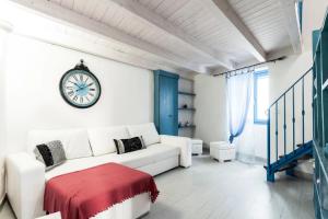 奥斯图尼Le Piccole Case Bianche的白色的客厅配有白色的沙发和时钟