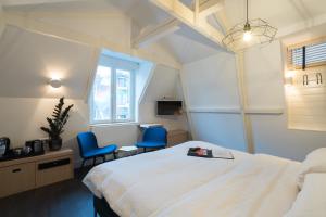 阿姆斯特丹阿米司塔特酒店的酒店客房,配有一张床和两张蓝色椅子