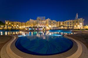 科威特Copthorne Al Jahra Hotel & Resort的一座大型游泳池,在晚上在建筑前