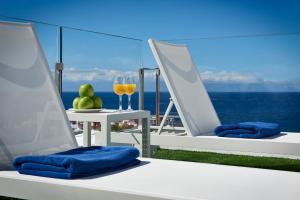 阿德耶火烈鸟海滩伴侣公寓的阳台上摆放了两把椅子和一杯葡萄酒