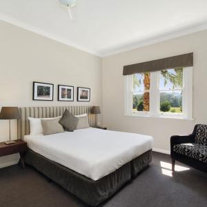 波拉尔佩博斯克雷格本度假酒店的卧室配有一张白色大床和一把椅子