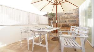 塞萨利内斯Sa Tanqueta的一张白色的桌子和椅子,配有雨伞