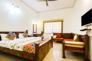 斋浦尔Hotel Raj Kothi Jaipur airport的一间卧室配有两张床、一台电视和一张沙发