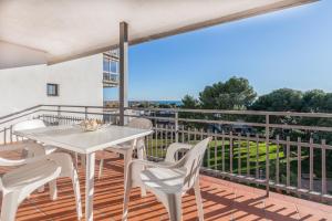 坎布里尔斯Agaró Cambrils Apartments的阳台的庭院配有白色的桌椅