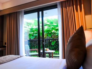 努沙杜瓦The Nest Hotel Nusa Dua的一间卧室设有一张床,享有阳台的景色