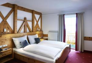 萨尔巴赫JUFA Alpenhotel Saalbach的一间卧室配有一张大床和木制床头板