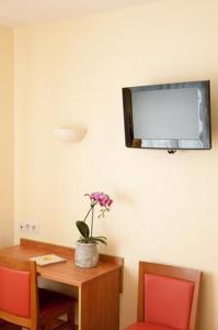 圣让-德蒙罗宾森酒店的一间设有桌子和墙上电视的房间