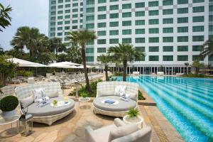 雅加达Hotel Mulia Senayan, Jakarta的一个带游泳池和椅子的度假胜地和一座建筑
