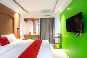 茂物RedDoorz Apartment at Bogor Valley的酒店客房,设有一张带绿色墙壁的床