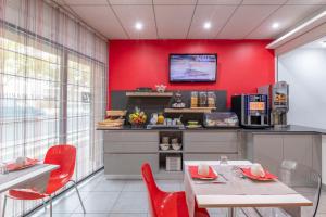 拉罗谢尔Lagrange Apart'Hotel l’Escale Marine的一间拥有红色墙壁和桌椅的用餐室