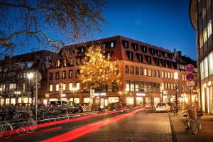 明斯特H.ostel Münster的夜间的城市街道,有圣诞树和建筑