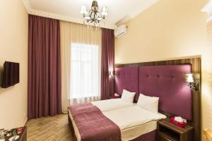 敖德萨Hotel Baron的一间卧室配有一张大床和紫色床头板