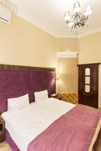 敖德萨Hotel Baron的一间卧室配有一张大床和紫色床头板