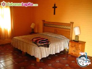 马萨米特拉Cabañas Lupita 31的卧室配有一张床,墙上有十字架