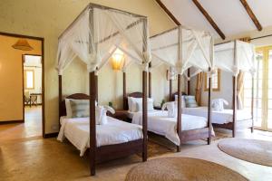 阿鲁沙Kili Villa Kilimanjaro Luxury Retreat的一间卧室配有四张带白色床单的四柱床