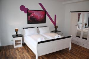柏林舍恩贝格公寓的卧室配有白色床,墙上挂有粉红色的画作