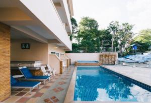 卡塔海滩Kata Sun Beach Hotel的一座房子旁的游泳池,配有蓝色的椅子