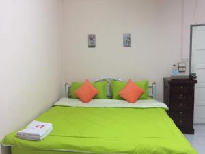 苏安庞班帕爵穆素安蓬旅馆的一间卧室配有带橙色枕头的绿色床