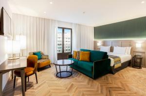 格拉纳达Eurostars Puerta Real的酒店客房配有床、沙发和桌子。