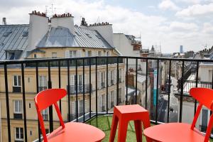 巴黎快乐文化约瑟芬酒店的阳台配有红色椅子,享有城市美景
