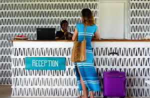 吉汶瓦Zanbluu Beach Hotel的站在登记册上的身着蓝色衣服的女人