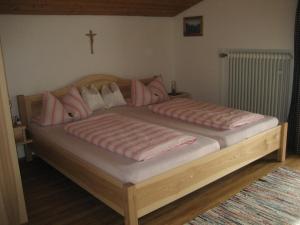 伦格里斯Gästehaus Proisl的一张带粉红色枕头的木床和墙上的十字架