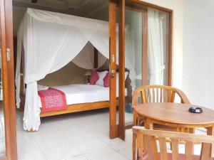 乌布拉卡旅馆的一间卧室配有一张天蓬床和一张桌子
