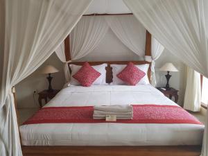 乌布拉卡旅馆的卧室配有带粉红色枕头的大型白色床