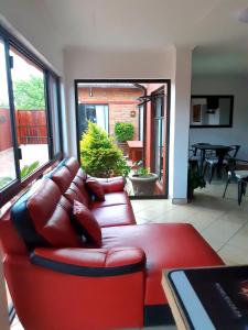 龙杜Niilo's Guesthouse的客厅配有红色皮革沙发和桌子