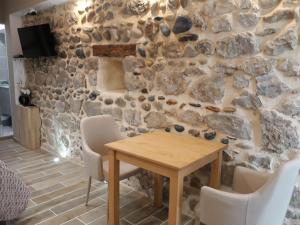 瓦朗斯Studio mistral的一间设有石墙和木桌及椅子的用餐室