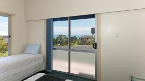 阿希帕拉Ahipara Bay Motel的一间卧室设有一张床和一个大型玻璃窗