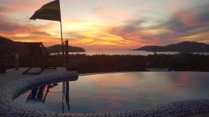 锡瓦塔塔内霍Casa Arcoiris Zihuatanejo B&B的一个带椅子的游泳池,享有日落美景