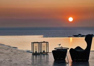 伊亚Santo Pure Oia Suites & Villas的海洋上的日落,配有桌椅