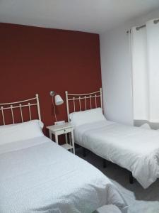 RocianaHostal Monteluna的一间卧室配有两张床和一张带台灯的桌子