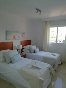 福恩吉罗拉Club La Costa World Resort的白色客房的两张床,设有窗户