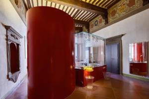 锡耶纳Palazzetto Rosso - Art Hotel的带浴室的客房内的红色花瓶