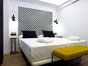 巴利亚多利德Hotel Colón Plaza的一间卧室设有两张床和黄色长凳