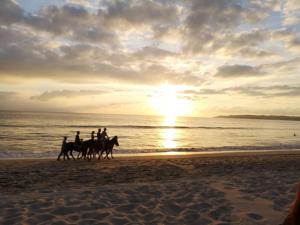 布塞里亚斯Depto. Hanna #5的一群人在日落时分在海滩上骑马