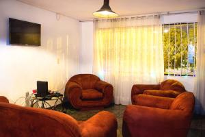 波哥大Bababuy Hostel的客厅配有两把椅子和电视