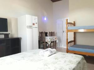 里约达欧特拉斯Suítes a Beira Mar的客房设有一张床、一台冰箱和一台电视。