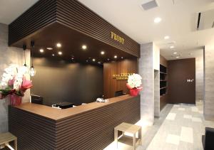 金泽Hotel Trend Kanazawa Ekimae的酒店大堂设有前台,并鲜花盛开