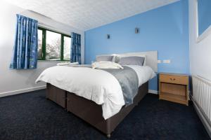 米尔顿凯恩斯National Badminton Centre Lodge & Health Club的蓝色的卧室设有一张大床和一个窗户
