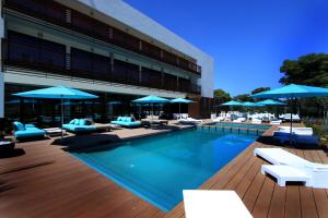 胡塞马绍阿尼酒店（胡塞马湾）的一座大楼内的游泳池,配有椅子和遮阳伞