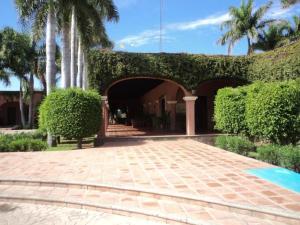 纳沃华Hotel Hacienda Cazadores的一座有拱门、树木和庭院的建筑