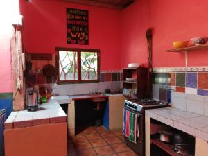BalgueLazy Crab Hostel的厨房设有红色的墙壁和炉灶。 顶部烤箱