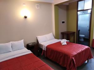 特鲁希略Hotel Plaza Bolognesi 344的一间设有两张床和红色毯子的房间