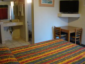 South El Monte美国旅馆的一间卧室配有一张床、一张桌子和一台电视