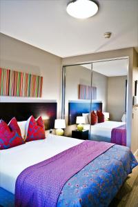 悉尼Quest Mascot的一间卧室配有两张带紫色和红色枕头的床