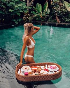 乌布河奈度假酒店的水里一个比基尼的女人,带一个食物托盘
